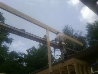 Carpenter setting a ridge beam over a new addition frame — Ice Dam Removal by Roofing Brothers in Hollansburg