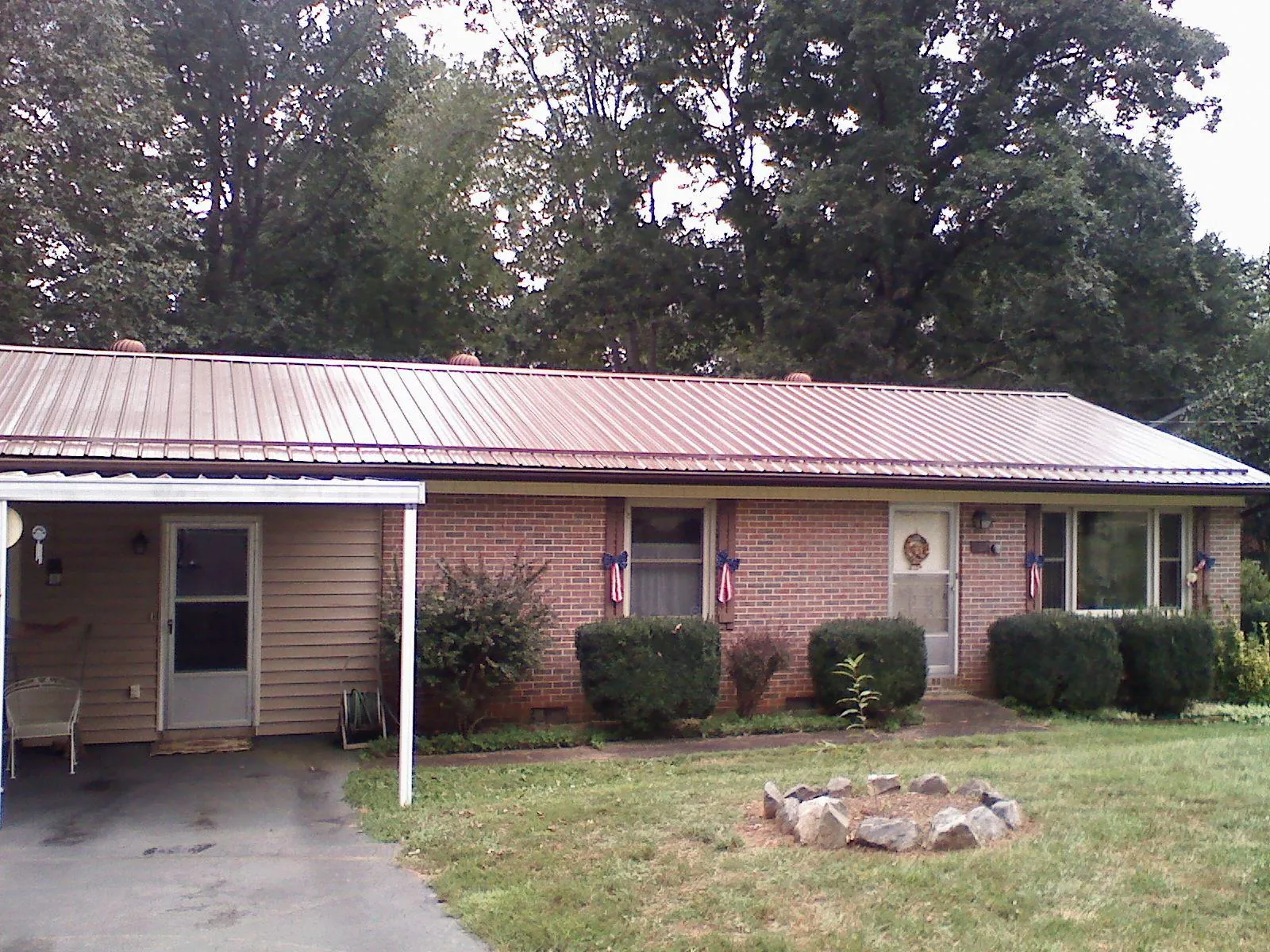 Bronze metal roof and carport on a brick ranch home — Roof Repair work by our crew in Hollansburg