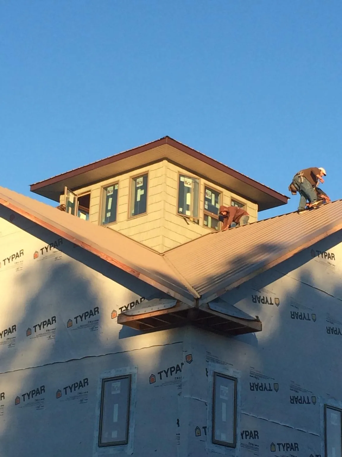 Roofers working around a rooftop cupola on a new metal roof at sunset — Roof Waterproofing in Hollansburg by Roofing Brothers
